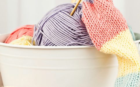 Tin bucket with yarn and the start of a scarf being knitted.