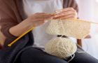 Close up on woman's hands knitting. Sitting on old armchair near window